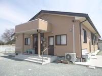 外装の色が茶色の建物で入り口前にコンクリートの階段がある写真
