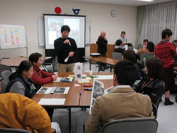 3班の方の1人の男性が立って話をしているのを聞いているメンバーの写真