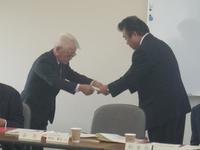 町長が白髪の審議会会長へ諮問書を手渡している写真