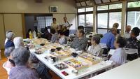 ギター片手の分館長の演奏を聴いている敬老会の人達の写真