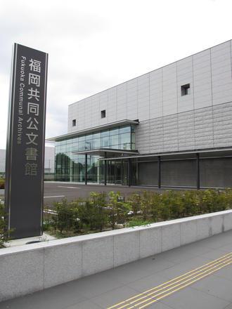手前に「福岡共同公文書館」と書かれた看板があり、奥にグレーの建物が見えている写真