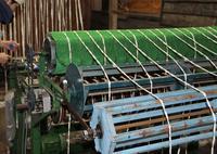 上段に緑色の機械中段、下段にも同じ長さの機械が取り付けられ太い糸がからまっているくくりの工程の写真