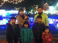 イルミネーションが点灯されている前で宮崎さん夫婦と子ども5名の家族写真