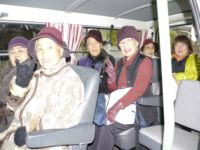 笑顔で買い物支援のバスに乗車している高齢者の方々の写真