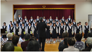 舞台に立つ久留米信愛女学院合唱部の演奏を聴いている人達の写真