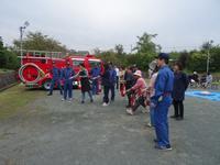 消防車の横で1列に並んだ参加者達が放水の訓練をしている写真