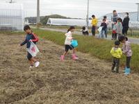 子ども会活動でゴミ袋やバケツをもち畑の中にはいっている子供達の写真