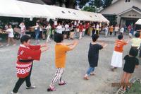 よど夏祭り会場で円になり踊りを踊っている参加者達の写真