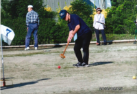 グランドゴルフを楽しんでいる紺色の服を着た男性がボールを打つ瞬間の写真